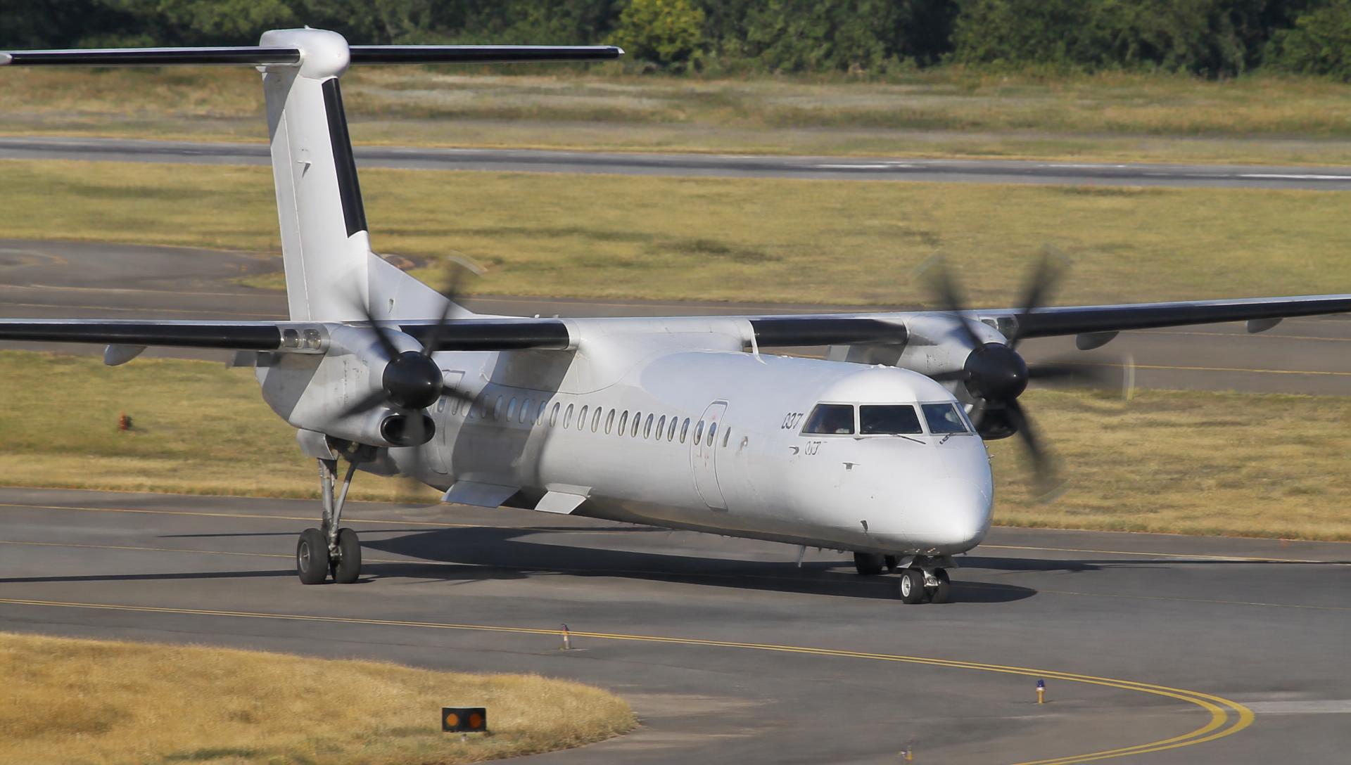 DHC-8 and Q400 taxiing on an airport taxiway in daylight